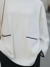 High-Neck Relaxed Sweater With Black Trim And Button Accents